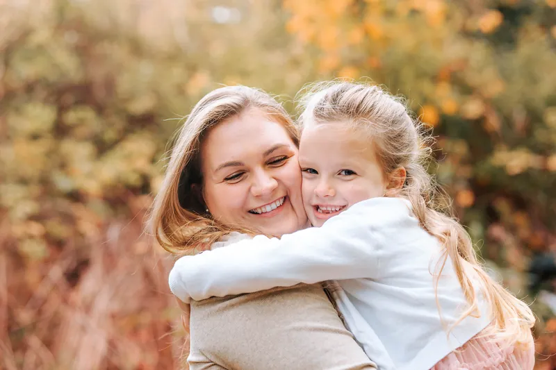 A mum and daughter sharing a big cuddle among autumn colours
