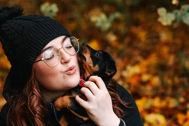 A young woman kissing her little dog in autumn woodland