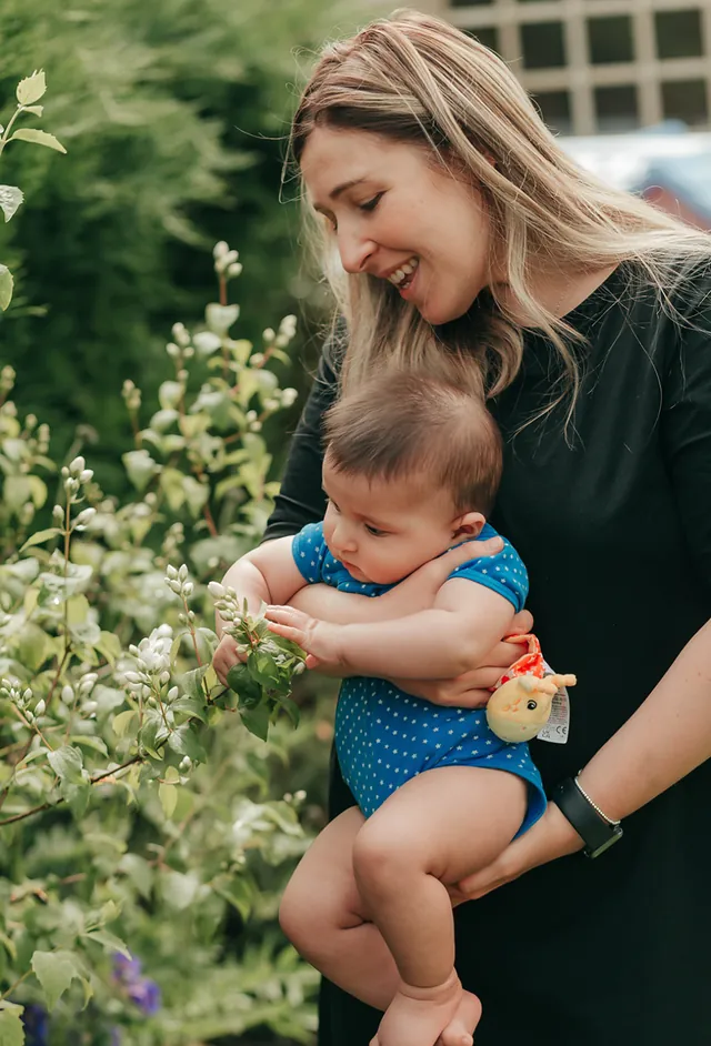 A mum holding her baby among the flowers in a summer garden