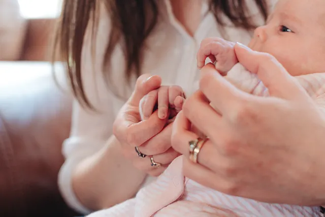 A newborn's tiny hand gripping mum's finger